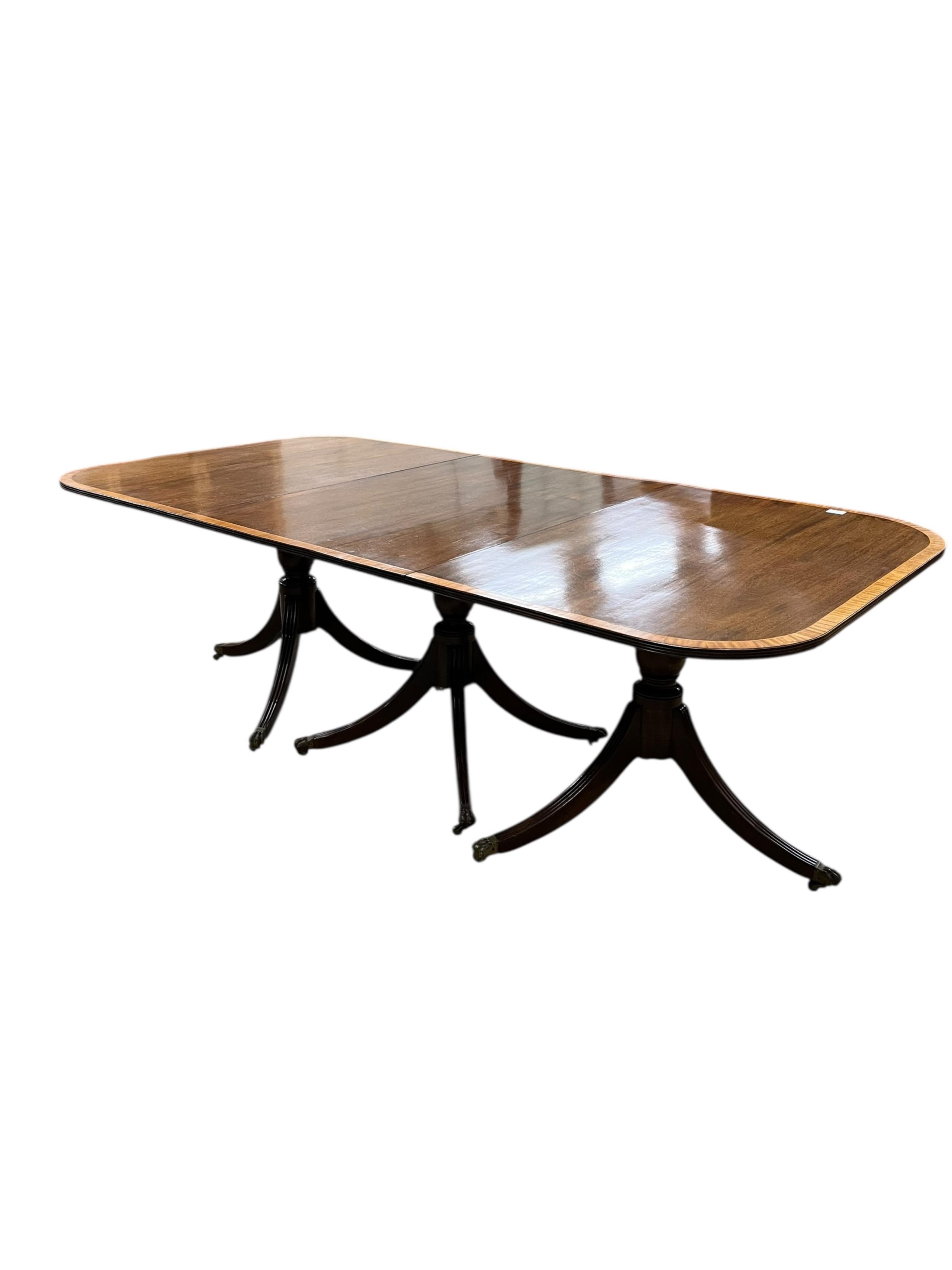 A Regency style mahogany and satinwood banded three pillar dining table, width 320cm extended, two spare leaves, depth 114cm, height 74cm